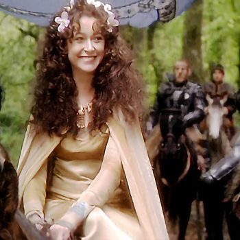 Cherie Lunghi as Guinevere in John Boorman's "Excalibur" radiates regal beauty amid the knights of Camelot. Woman in golden medieval gown with flowing curls surrounded by armored knights in forest setting from 1981 film.